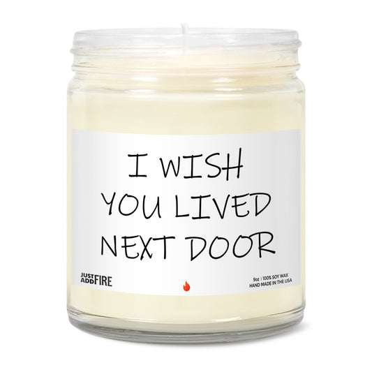 I Wish You Lived Next Door Soy Wax Candle by Just Add Fire. Features USA made 100% natural soy wax, cotton wick, and safe fragrances and essential oils. Image shows the candle with no lid, unlit. 
